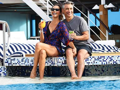 Couple relaxing by the pool on board Regatta